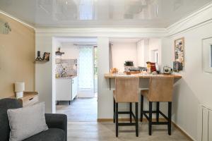a kitchen and living room with a counter and chairs at La P'tite Escapade - à 25 min de Caen in Creully