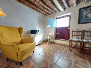 ein Wohnzimmer mit einem gelben Stuhl und einem Fenster in der Unterkunft Casa Almachar in Cómpeta