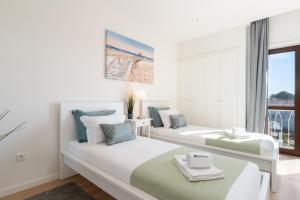 two beds in a white room with a window at Bright & Spacious Retreat with Balcony by HostWise in Porto
