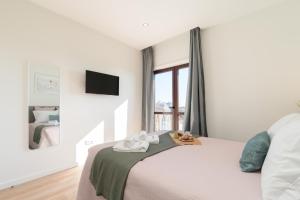 a white bedroom with a bed and a window at Bright & Spacious Retreat with Balcony by HostWise in Porto