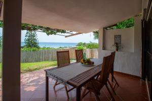 a dining room table with chairs and a view of the ocean at Villa Marina in Campu Longu