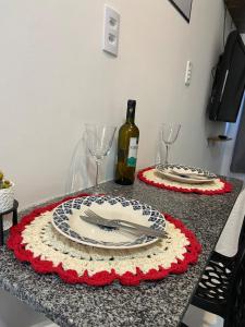 a table with two plates and a bottle of wine at Flat Adenil Falcão - By Temporada Expert -Moderno e Próximo ao centro in Feira de Santana