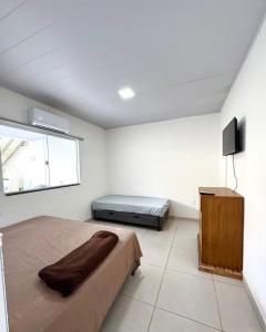 a bedroom with a bed and a flat screen tv at Casa na praia, Balneário de Carapebus in Serra +11 photos