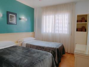 a hotel room with two beds and a window at Apartamentos Eldorado in Lloret de Mar