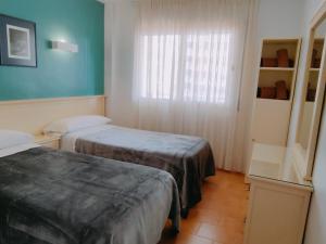 a hotel room with two beds and a window at Apartamentos Eldorado in Lloret de Mar