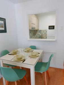 a dining room with a white table and green chairs at Apartamentos Eldorado in Lloret de Mar