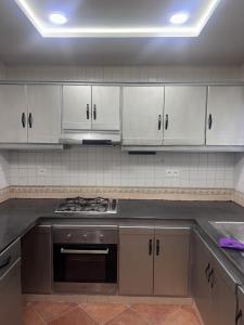 a kitchen with white cabinets and a stove top oven at Marinasmir Jawhara in Fnidek