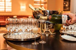 a person pouring a bottle of wine into wine glasses at Grand Poet Hotel and SPA by Semarah in Rīga
