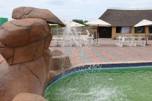 a fountain in front of a swimming pool at Phendulani Lodge & Park in Calcutta