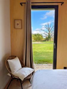 a bedroom with a wicker chair and a window at Maisons du lac in Écollemont