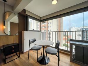ein Esszimmer mit Tisch und Stühlen und einem großen Fenster in der Unterkunft Handy Paraíso condomínio com piscina ao lado do Ibirapuera in São Paulo