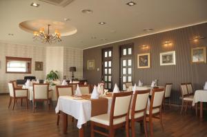 a restaurant with white tables and chairs and a chandelier at Hotel Srbija in Vršac