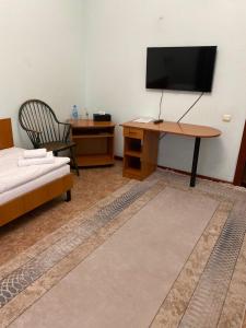 a room with a bed and a desk with a television at Момент in Yuzhnoukrainsk 