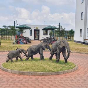 eine Statue von drei Elefanten, die auf dem Gras wandeln in der Unterkunft orana homes II in Ruiru + 2 Fotos