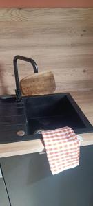 a black sink with a wooden spatula and a towel at Appartement La Marmotte Compreignac in Compreignac +10 photos