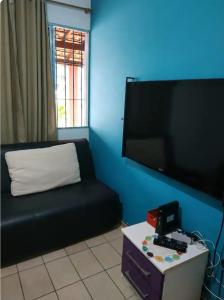a living room with a black couch and a flat screen tv at Casa Jardim do Mar - Ubatuba - Praia Grande in Ubatuba