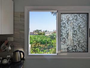 a kitchen window with a view of a garden at Villa Rebecca in Luxor