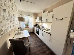 a kitchen with white cabinets and a table with a chair at Ferienwohnung Wiesenzauber - Ruhige Lage am Stadtrand von Leer & Rhauderfehn in Rhauderfehn