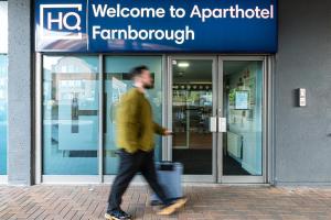 a man walking down a sidewalk in front of a store at HQ Aparthotel Farnborough in Farnborough