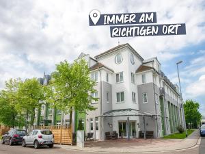 a white building with cars parked in front of it at ACHAT Hotel Leipzig Messe in Leipzig