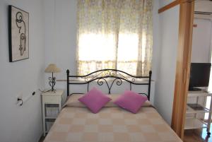 a bedroom with a bed with two pink pillows at Oasis Playa de Gandía in Gandía