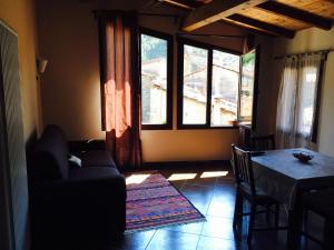 een woonkamer met een bank, een tafel en ramen bij La Casetta in Dolceacqua