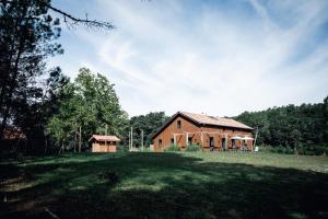 a large barn with a grassy field in front of it at La Maison des Pins contis in Saint-Julien-en-Born