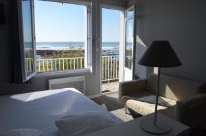 a bedroom with a bed and a balcony with the ocean at La Villa Saint Jean in Les Sables-d'Olonne