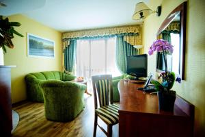 Hotel Pietrak في واغروويك: غرفة معيشة مع مكتب مع تلفزيون وأريكة
