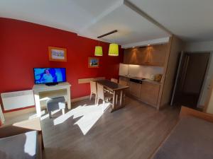 a living room with red walls and a table with a television at Charmant 2P au centre, balcon Sud, parking, animaux admis - FR-1-513-82 in La Tania
