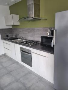 a kitchen with a stove and a sink and a refrigerator at Maison proche plage in Merlimont +4 photos