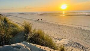 two people walking on the beach at sunset at Maison proche plage in Merlimont