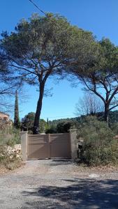 a gate in a driveway with a tree behind it at Les Cigales in Villelaure