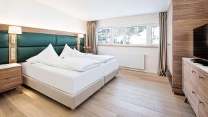 a bedroom with a large white bed and a television at THE NEW RONACHER Thermal Spa Hotel in Bad Kleinkirchheim +56 photos