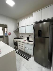 a kitchen with a stainless steel refrigerator and white cabinets at Apartamento Petúnia 2qto até 3 pessoas Res Unique in Goiânia