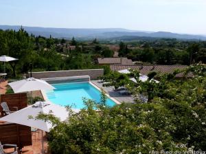 ein Swimmingpool mit zwei weißen Sonnenschirmen in der Unterkunft AU PIED DU VENTOUX in Flassan