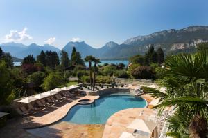 a swimming pool with a view of the mountains at Hôtel Les Grillons in Talloires