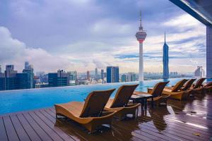 a rooftop pool with chairs and a view of the city at XING LUN KLCC Platinum Suites in Kuala Lumpur
