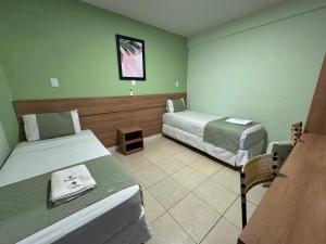 a hotel room with two beds and a table at Domus Hotel Veneza - Ipatinga in Ipatinga +13 photos