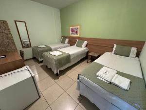 Habitación hospitalaria con 3 camas y espejo en Domus Hotel Veneza - Ipatinga, en Ipatinga