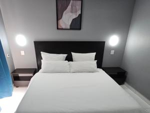 a bed with white sheets and pillows in a bedroom at Grand Diamond Lodge in Roodepoort +2 photos