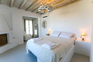 una camera da letto bianca con un letto e un lampadario di Manolia Luxury Private house by Mykonian Kazarte a Kalo Livadi Altre 40 foto