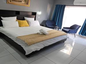 a bedroom with a large bed and two chairs at Grand Diamond Lodge in Roodepoort