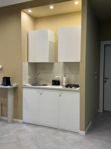 a kitchen with white cabinets and a sink at Appartamento Onda in Lido di Ostia +8 photos