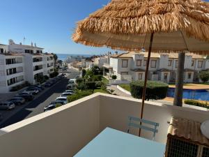 a table with a straw umbrella on a balcony at Apartamento Torre da Medronheira in Olhos de Água