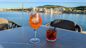 einen Tisch mit einem Glas und einem Drink darauf in der Unterkunft Honeymoon Seaview in St Paul's Bay