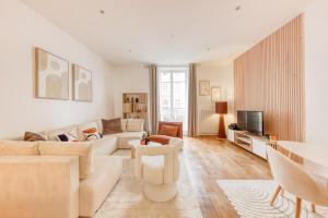 ein Wohnzimmer mit weißen Möbeln und einem Fernseher in der Unterkunft Arc & Luxe Champs-Elysées in Paris