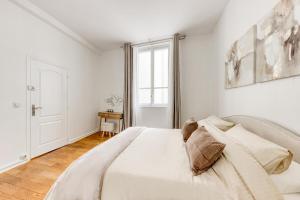 ein weißes Schlafzimmer mit einem großen Bett und einem Fenster in der Unterkunft Arc & Luxe Champs-Elysées in Paris