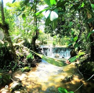 a hammock in front of a waterfall in a forest at Refúgio Boa Sorte , Sana -Macaé RJ in Sana