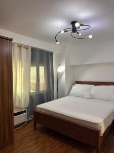 a bedroom with a bed with white sheets and a lamp at Cozy 2 BR 2 Bath Condo with Netflix and Karaoke near MRT EDSA in Manila +36 photos
